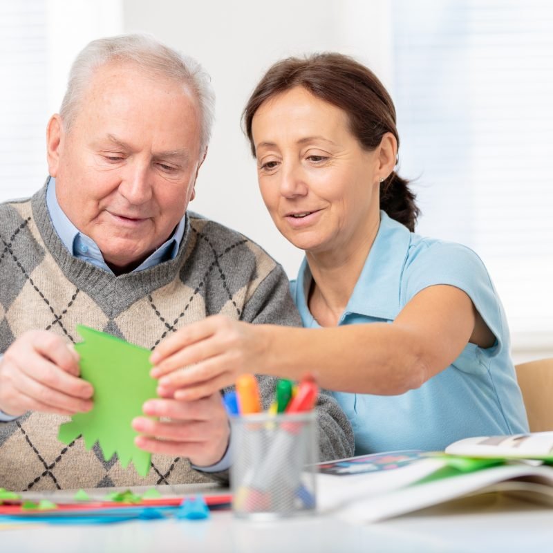 Nursing home: Senior man cutting paper with scissors